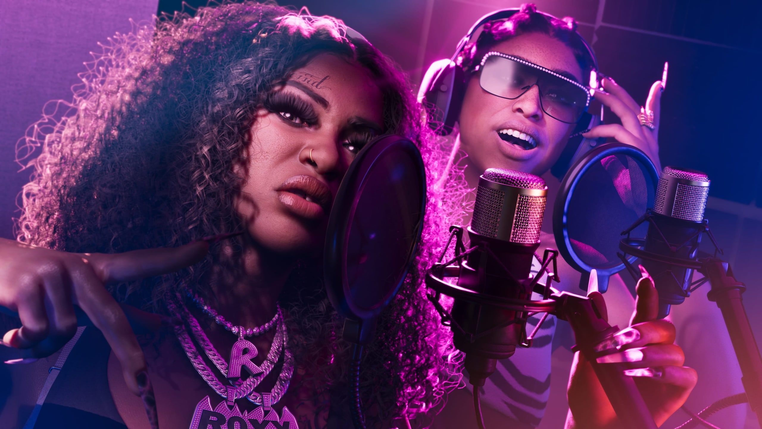 Bae-Luxe and Roxy, the Real Dimez, at the mics in a recording studio.